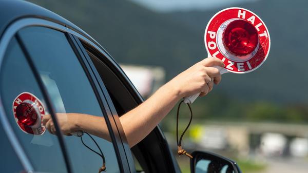 Ein Mann hält eine Anhaltekelle aus dem Fenster ei