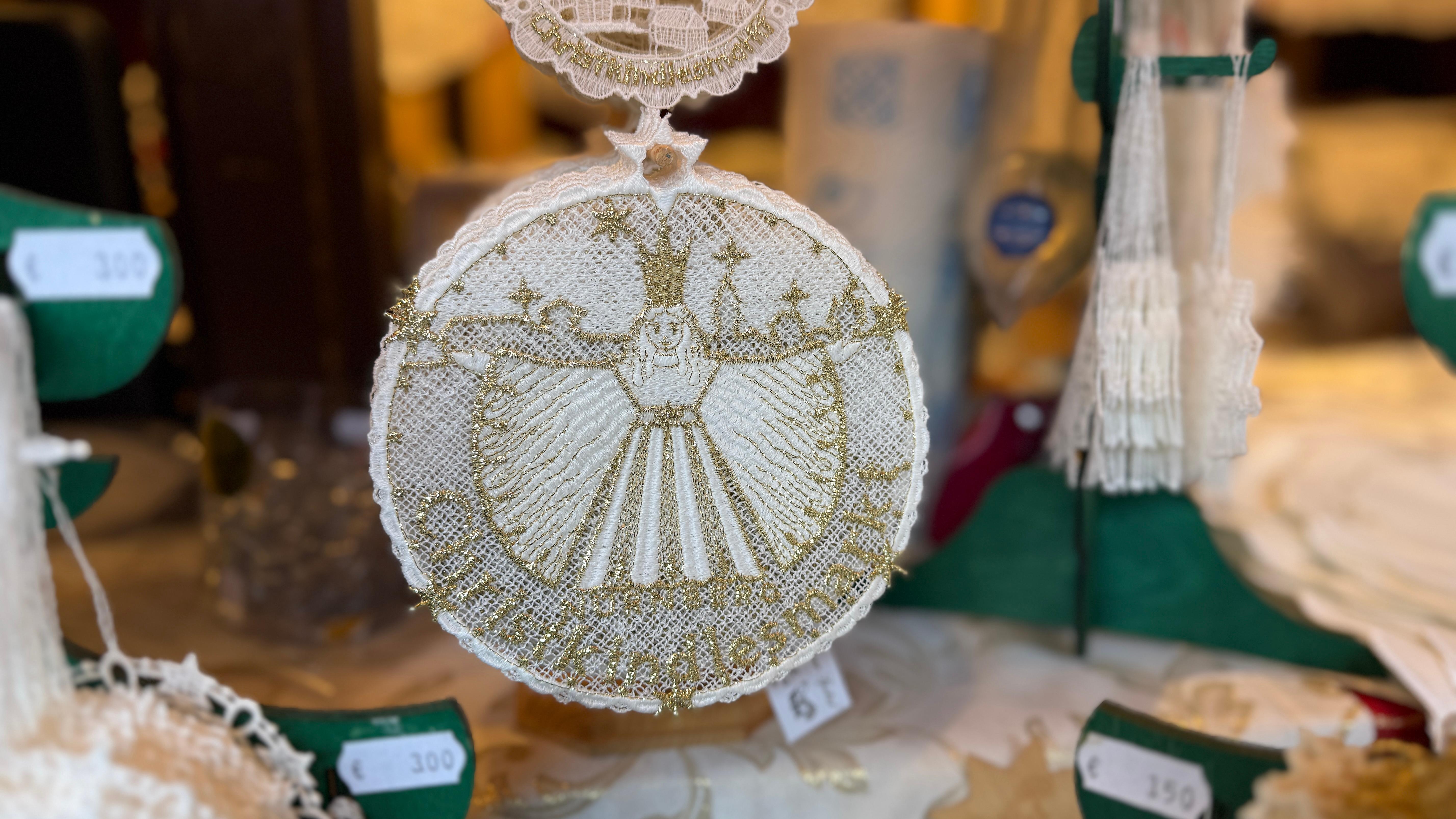 An der Bude 69 von Patrick Vogel finden wir ein Fensterbild aus Plauener Spitze mit dem offiziellen Christkindlesmarkt-Logo.