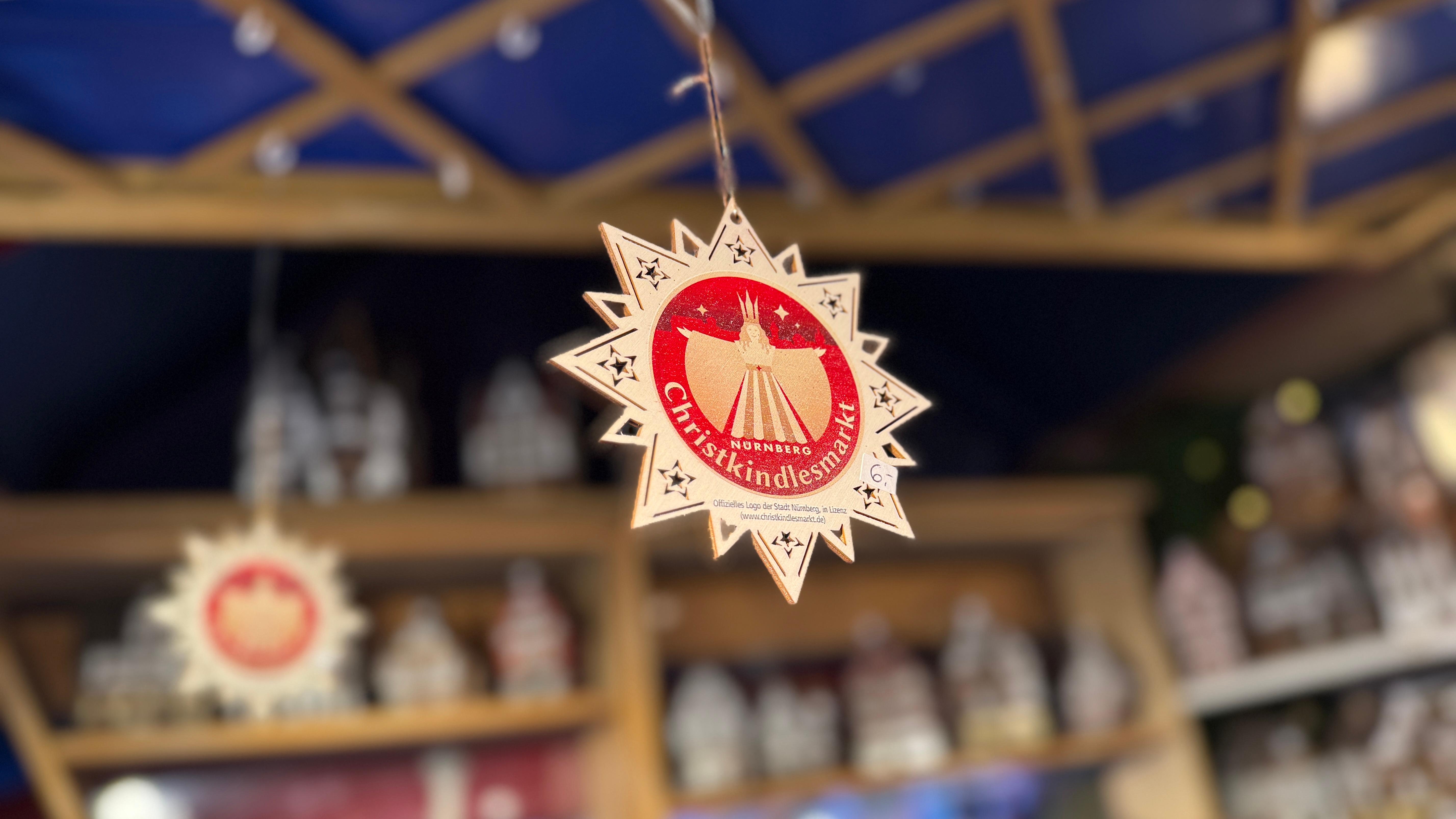 Bei Friedrich Barthelmes in Bude 34 gibt es sternf&ouml;rmige Holzanh&auml;nger mit dem Christkindlesmarkt-Logo.