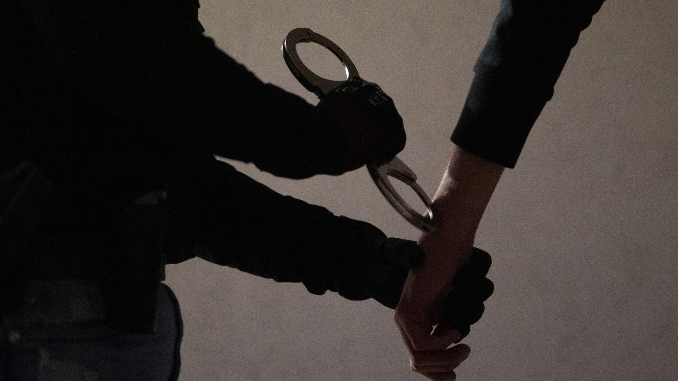 Eine Beamtin legt einem Mann Handschellen an. (zu 