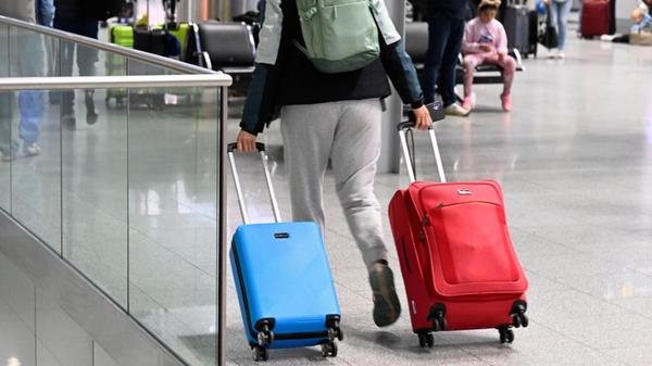 Ein Reisender schiebt seine Koffer im Abflug-Termi