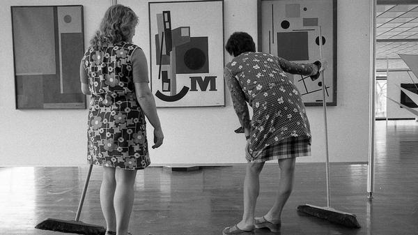In Kunstbetrachtung versunken: Einen Moment der Muße gönnen sich zwei Raumpflegerinnen auf unserem Motiv aus dem Jahre 1975, welches seinerzeit unter dem Titel "Kunstpflege" erschienen ist. Ihre geblümten Arbeitskittel bilden einen reizvollen Kontrast zu den ausgestellten abstrakten Kunstwerken. Um welche Ausstellung es sich handelt, ist leider nicht bekannt.
