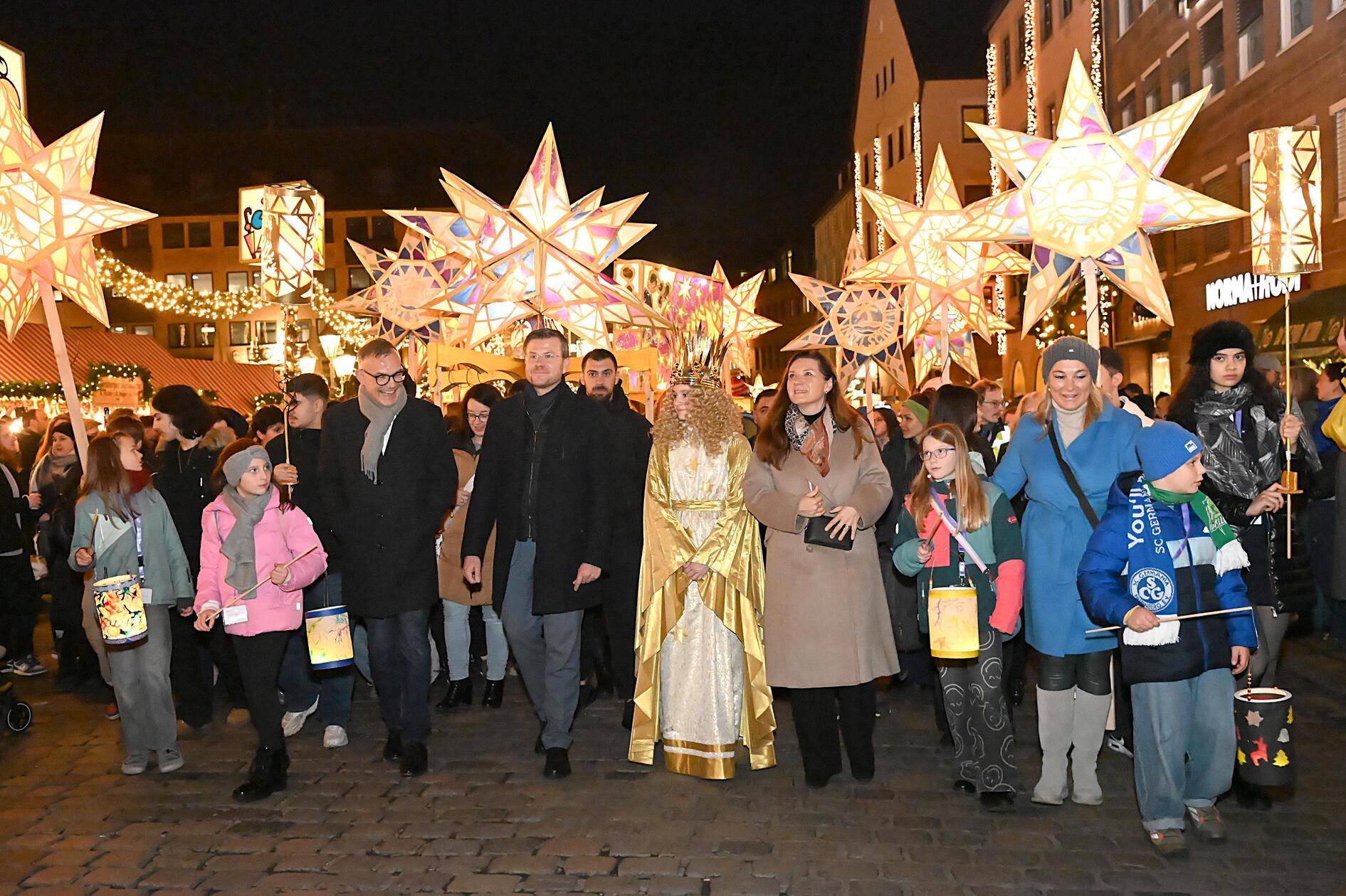 Nicht nur die kleinen Laternen, sondern auch die großen Lichter-Kunstwerke werden traditionell jedes Jahr von Nürnberger Schulkindern selbst gebastelt. 1000 von ihnen zogen beim nunmehr 75. Lichterzug von der Fleischbrücke über den Christkindlesmarkt bis hinauf zum Krippenspiel unterhalb der Kaiserburg. Angeführt wurden sie vom Nürnberger Christkind Nora Falk und Oberbürgermeister Marcus König.