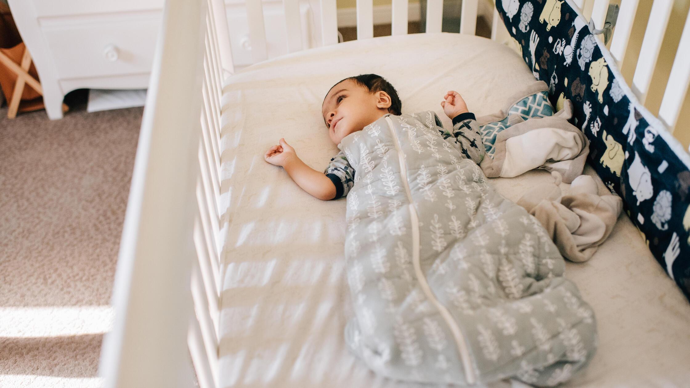 Baby boy lying awake in crib, high angle view