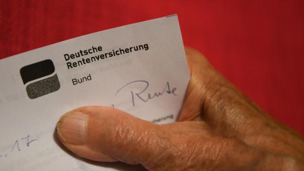 Eine ältere Frau hält ihren Rentenbescheid in der