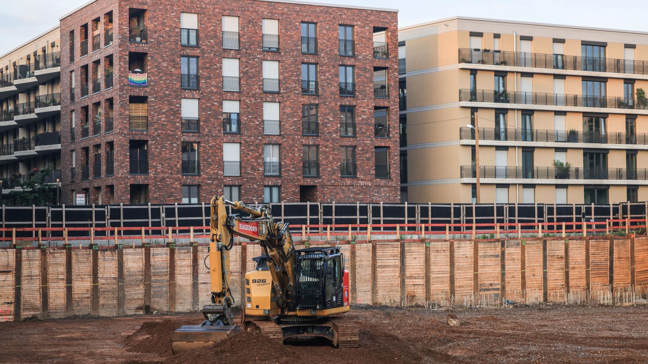 Ein Bagger stehet in einer Baugrube vor neugebaute