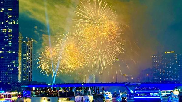 Das Silvesterfeuerwerk beleuchtet den Chao Phraya River in Bangkok, Menschen beobachten das Spektakel von Partybooten aus.