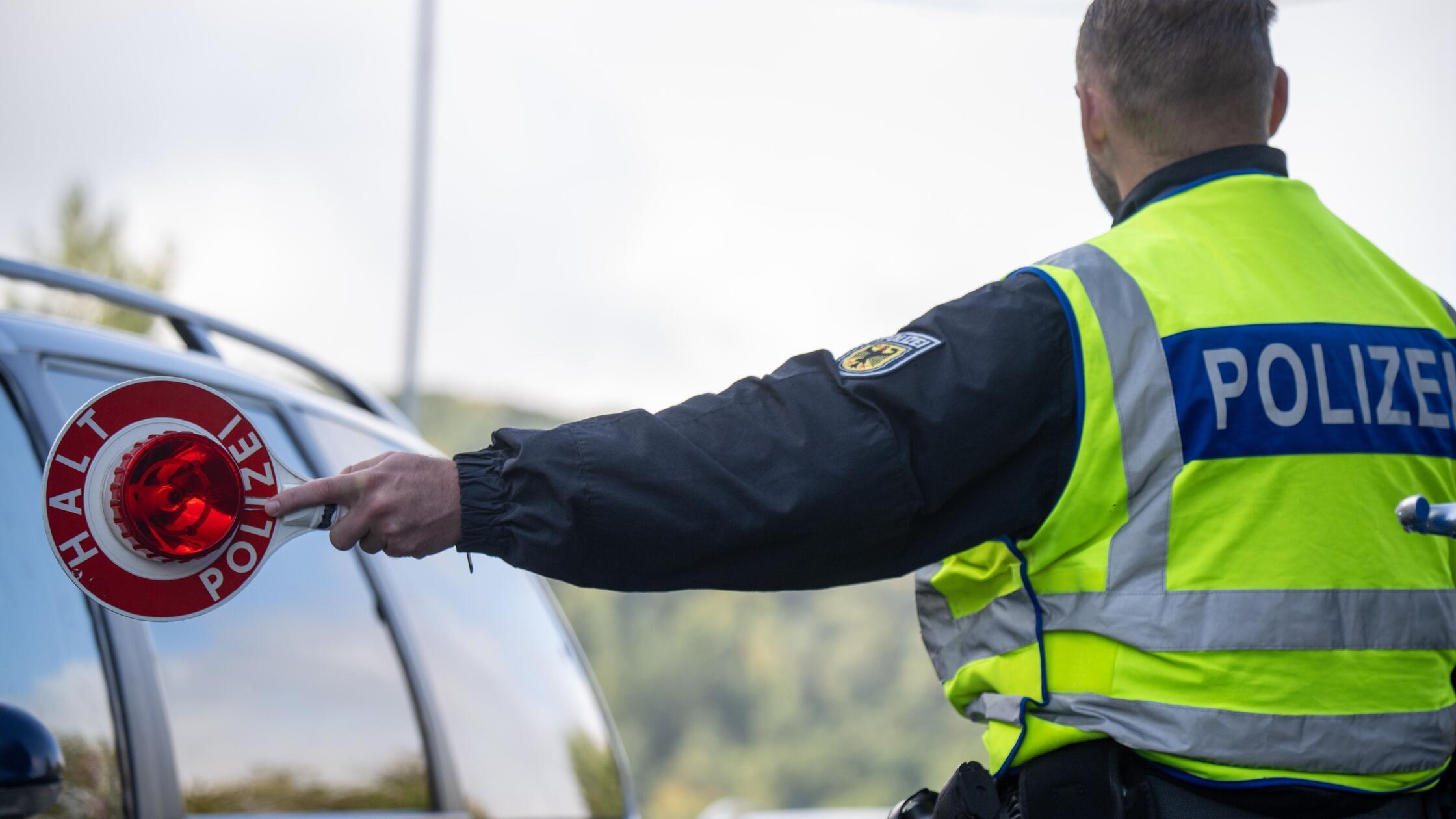 Ein Bundespolizist hält einen PKW zum Überprüfen d
