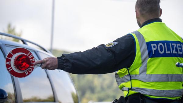 Ein Bundespolizist hält einen PKW zum Überprüfen d