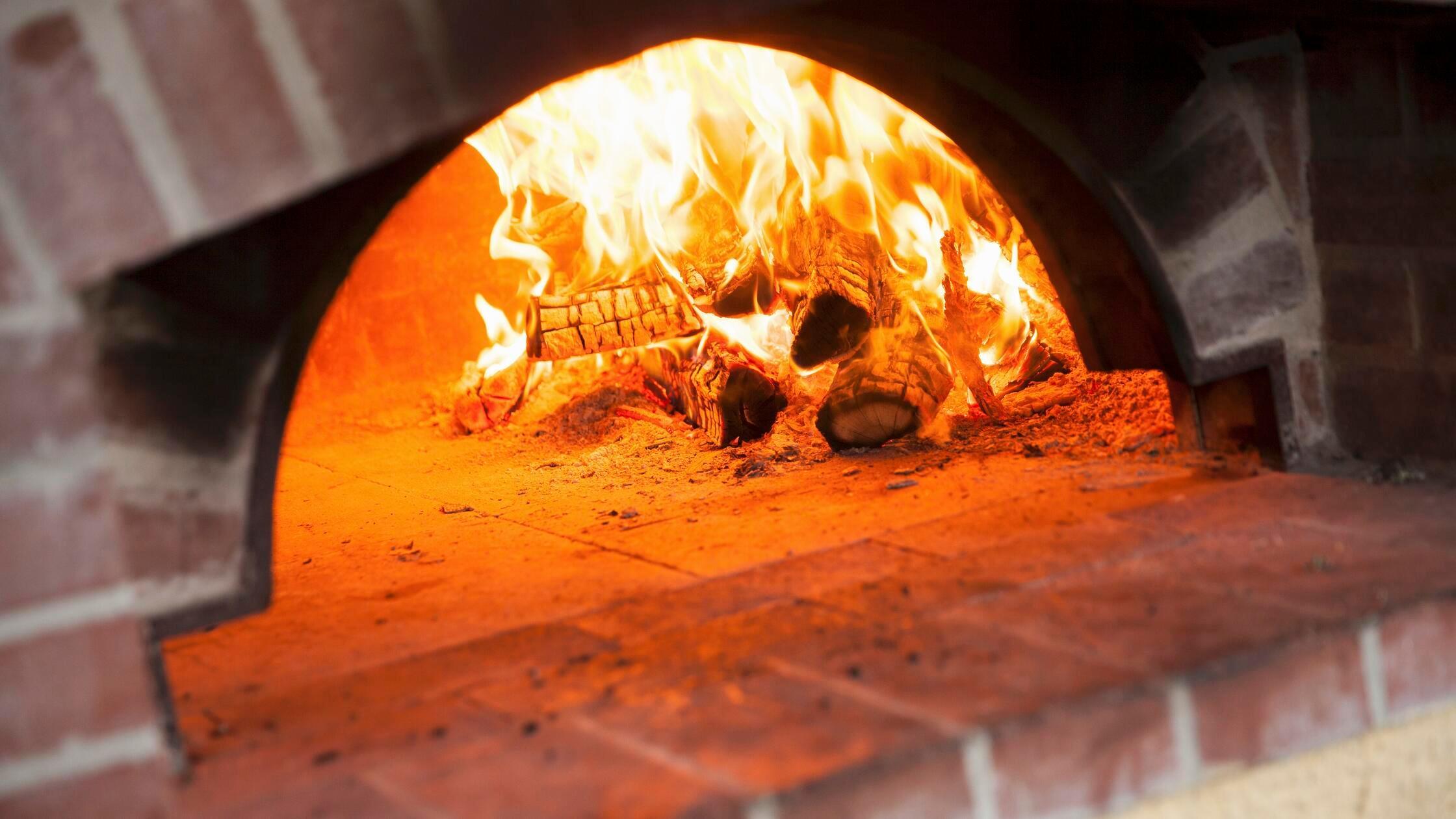 Brennendes Feuer im Holzofen einer Pizzeria