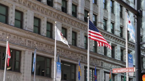 Rechts im Bild die Flagge Chicagos. Die zwei blauen Streifen stehen hierbei für den Chicago River und den Michigansee, die weißen Anteile für die Seiten der Stadt und die roten Sterne für einschneidende Geschehnisse in der Stadtgeschichte.