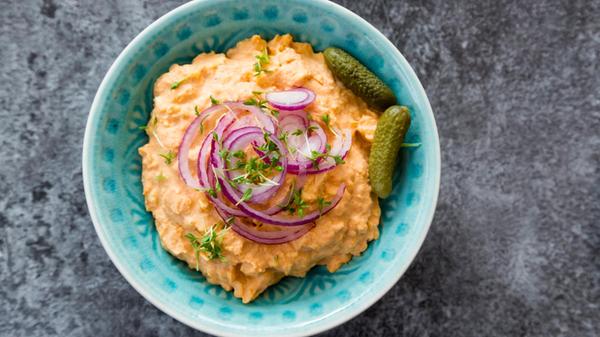 Bowl of Obatzda with gherkins, onion rings and cre