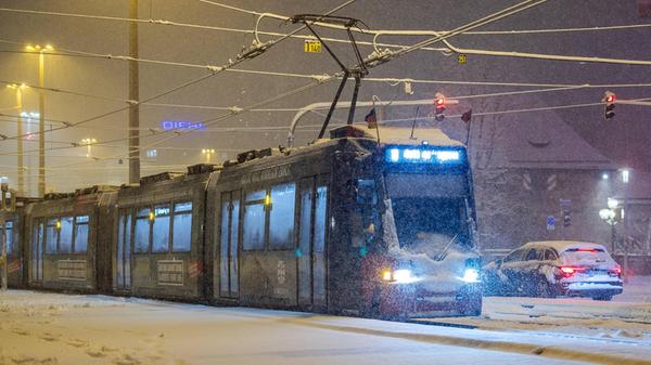 Eine stark verschneite Straßenbahn der Linie 8 fährt am späten Sonntagabend bei anhaltendem Schneefall in den Königstorgraben in Nürnberg ein. Am Montagmorgen wurde dann der Verkehr mehrerer Tram-Linien vollständig eingestellt.