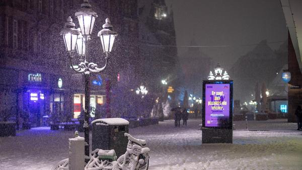 Zwei mit Schnee bedeckte Fahrräder stehen unter einer Laterne in der Innenstadt von Nürnberg.