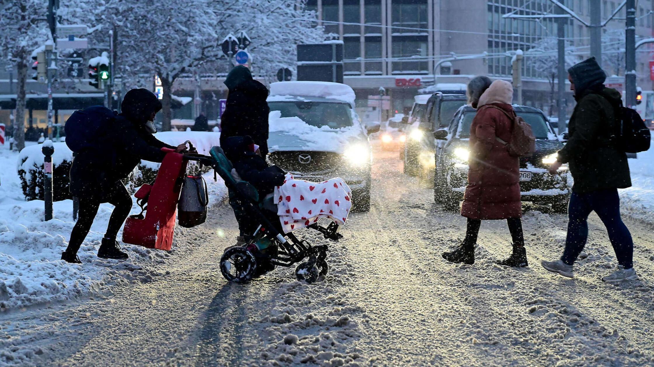 Nicht nur der Verkehr hatte zu kämpfen: Hier schiebt eine Mutter ihren Kinderwagen durch das Schneechaos.