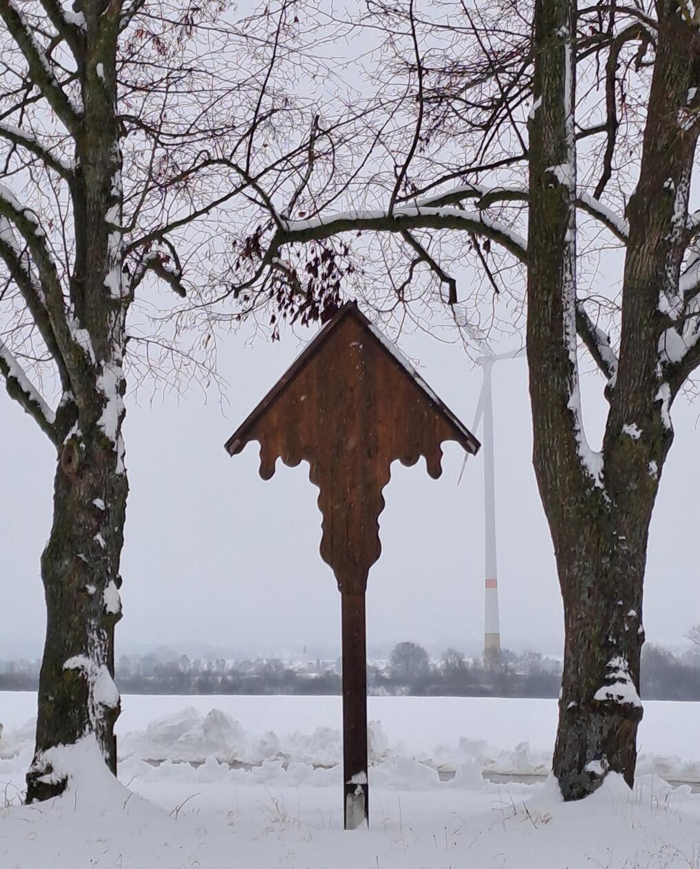 Noch ein Bild von Michael Harrer aus Jahrsdorf. Vorne das Feldkreuz zwischen den zwei Bäumen. Im Hintergrund ist eines der beiden Windräder im Schneetreiben zu sehen.