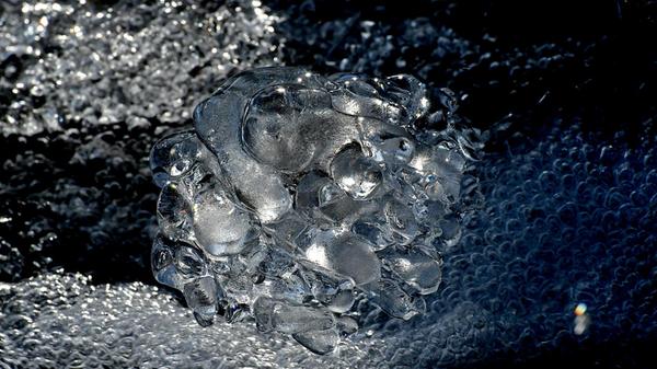 Dieses Eisgebilde, an einem Bach aufgenommen, erinnert an ein Schmuckstück, etwa ein Kettenanhänger oder Ohrring.