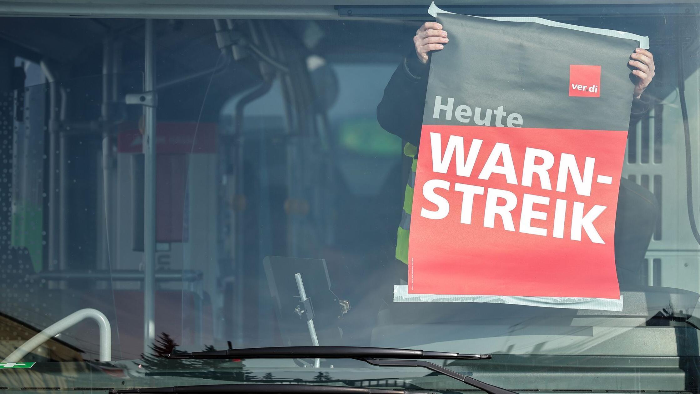 Ein Mitarbeiter befestigt ein Warnstreik-Plakat wä