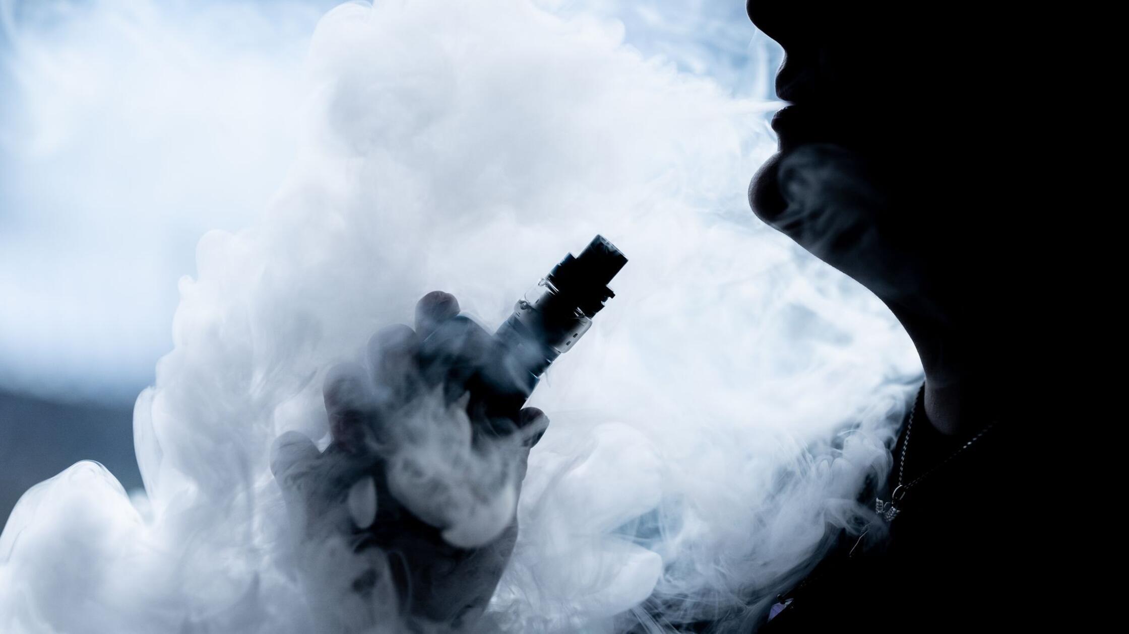 Eine junge Frau raucht in ihrer Wohnung mit einer 