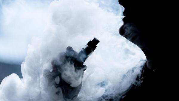 Eine junge Frau raucht in ihrer Wohnung mit einer