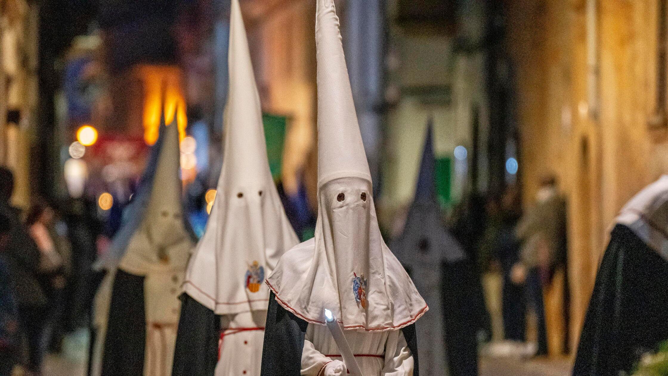Kapuzenbrüder mit konischen Hüten, die als Masken 