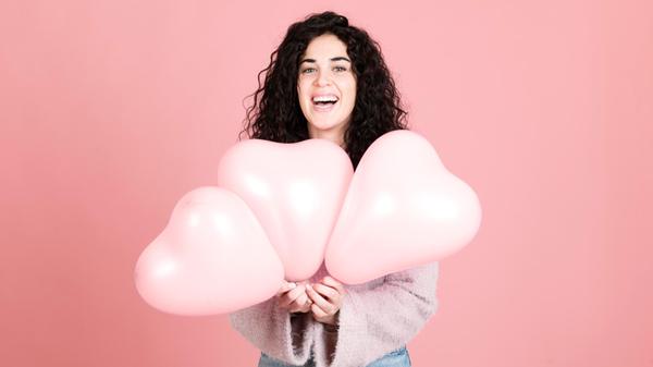 Happy young woman standing with heart shaped ballo