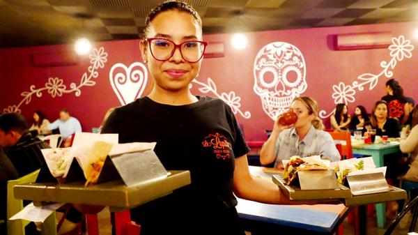 In einer authentischen Taqueria serviert diese Kellnerin leckere Tacos.