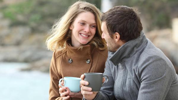 Happy couple of adults talking in winter on the be