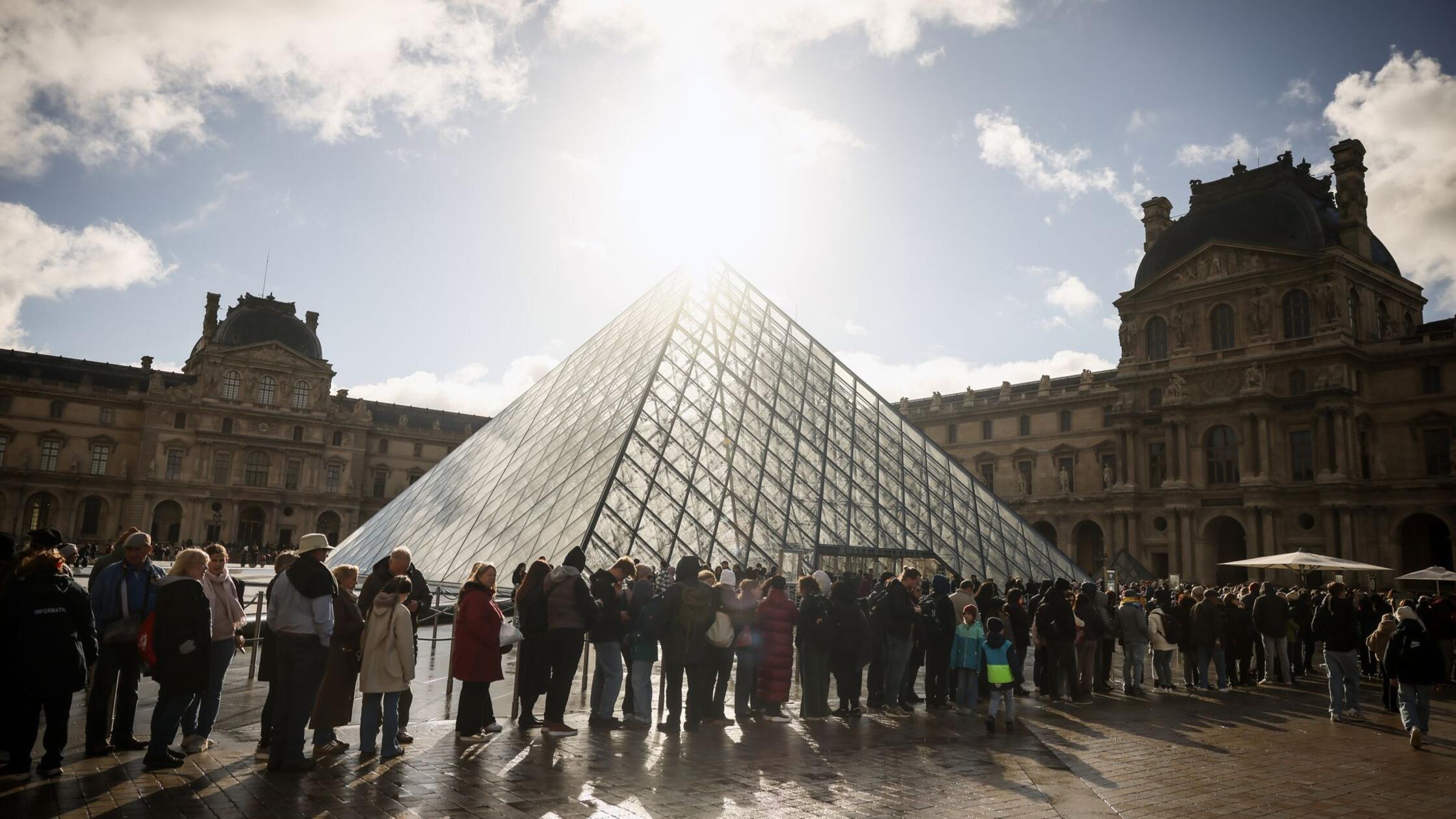 Besucher stehen vor der Glaspyramide im Louvre in 