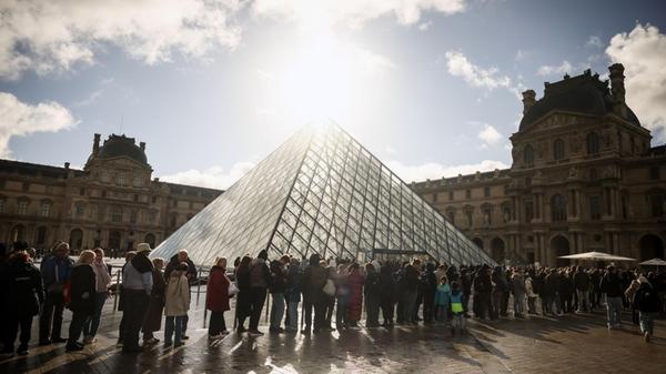 Besucher stehen vor der Glaspyramide im Louvre in