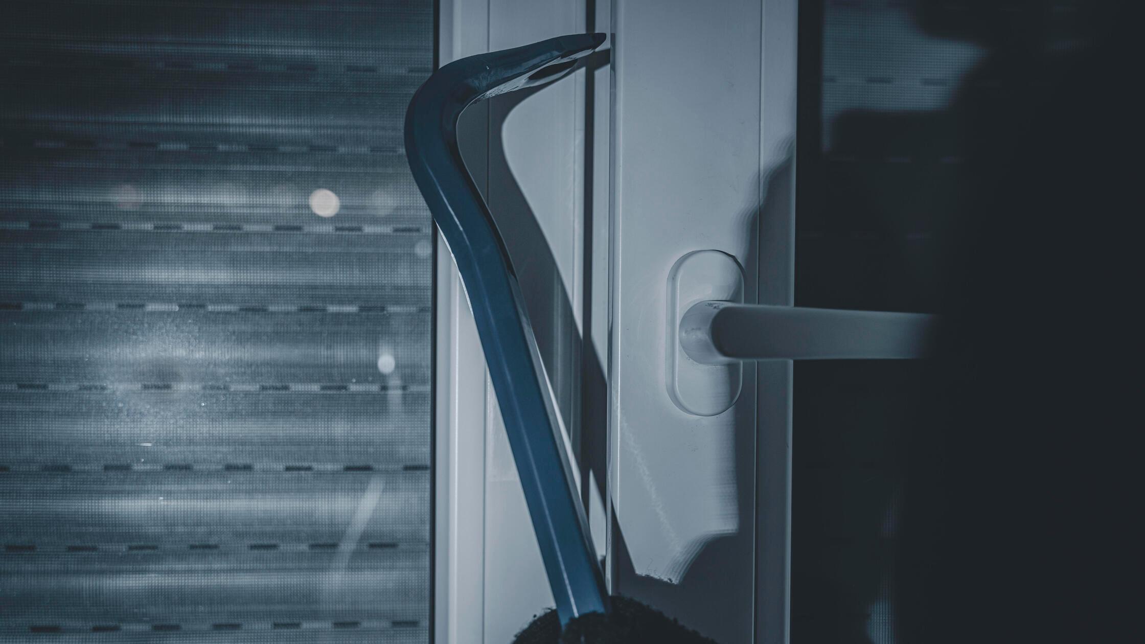 maskierter Einbrecher bricht mit Brecheisen in ein