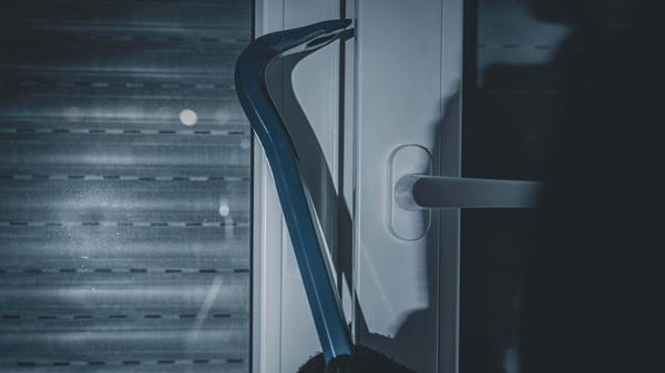 maskierter Einbrecher bricht mit Brecheisen in ein