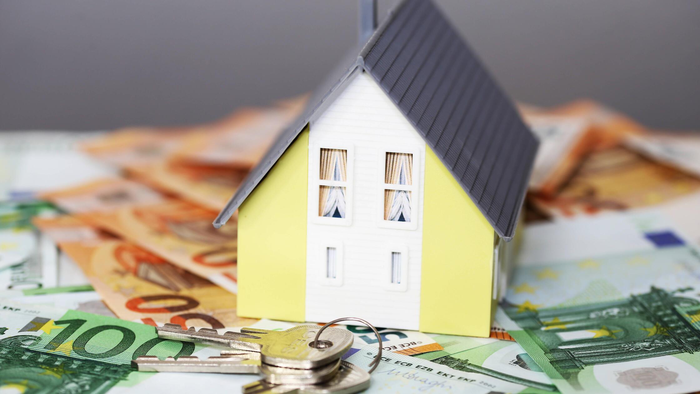 Konzeptfoto mit Modelhaus, Euronoten und Münzen **