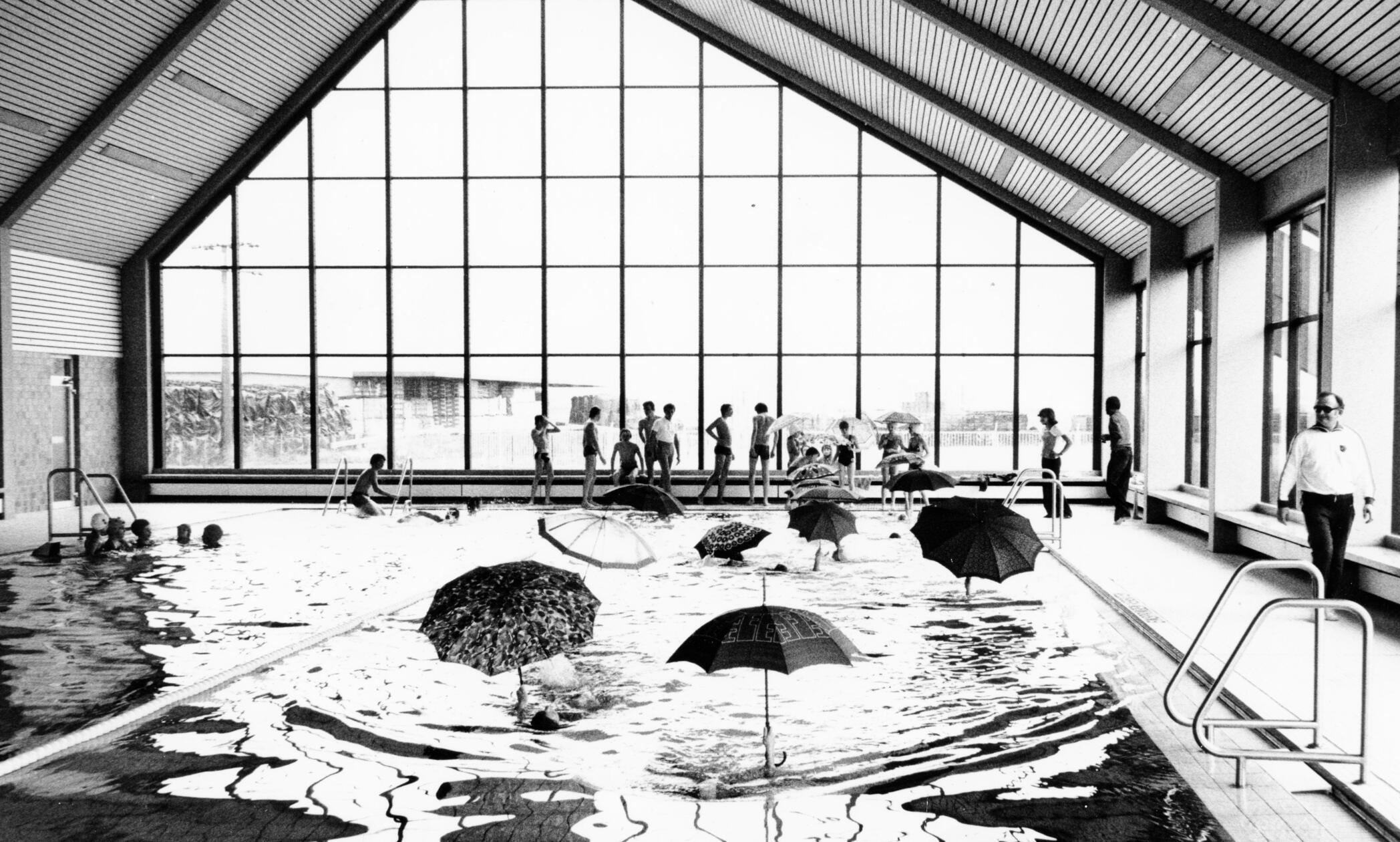 „I'm swimming in the rain!“ konnten Badegäste im Hallenbad in Stadeln aus gegebenem Anlass eine Weile lang singen, denn es regnete durch das Dach hinein. An dem erst im Jahr 1973 eröffneten Bad mussten bereits 1977 Renovierungsarbeiten durchgeführt werden. Auf unserem Archivbild sieht man nicht etwa die Schirmherren des Schwimmbades, sondern einige Badegäste, die bei den Feierlichkeiten zur Wiedereröffnung trockenen Humor bewiesen.