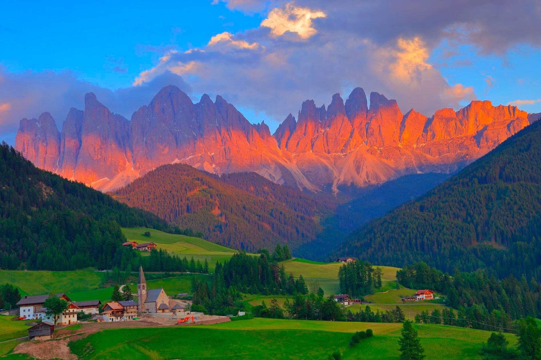 Das Dorf Santa Magdalena vor den Dolomiten im Val di Funes: Das idyllische Südtirol erlebt einen derart großen Ansturm an Touristen, sodass Land- und Almwirte sowie Anwohner sich bereits genötigt sahen, selbst Absperrungen und Drehkreuze anzubringen. Immer mehr Gemeinden setzen auf hohe Maut- und Parkplatzgebühren, um Besucher abzuschrecken und den Andrang zu reduzieren. In der Alpenregion befürchtet man sogar einen zeitnahen Kollaps (siehe Link im rechten Eck des Fotos).