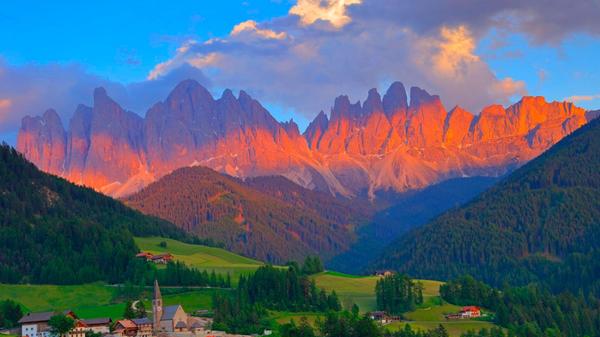 Das Dorf Santa Magdalena vor den Dolomiten im Val di Funes: Das idyllische Südtirol erlebt einen derart großen Ansturm an Touristen, sodass Land- und Almwirte sowie Anwohner sich bereits genötigt sahen, selbst Absperrungen und Drehkreuze anzubringen. Immer mehr Gemeinden setzen auf hohe Maut- und Parkplatzgebühren, um Besucher abzuschrecken und den Andrang zu reduzieren. In der Alpenregion befürchtet man sogar einen zeitnahen Kollaps (siehe Link im rechten Eck des Fotos).