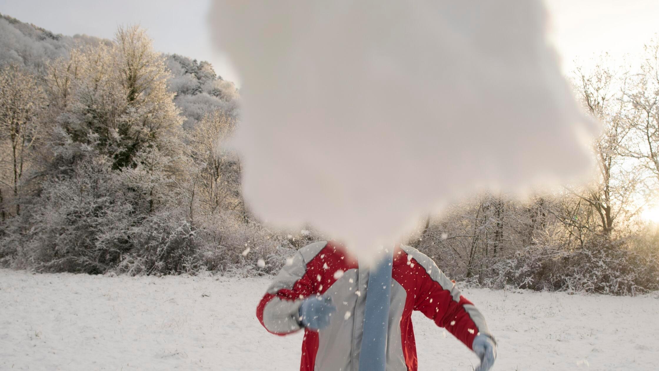 Man throwing a snowball in park