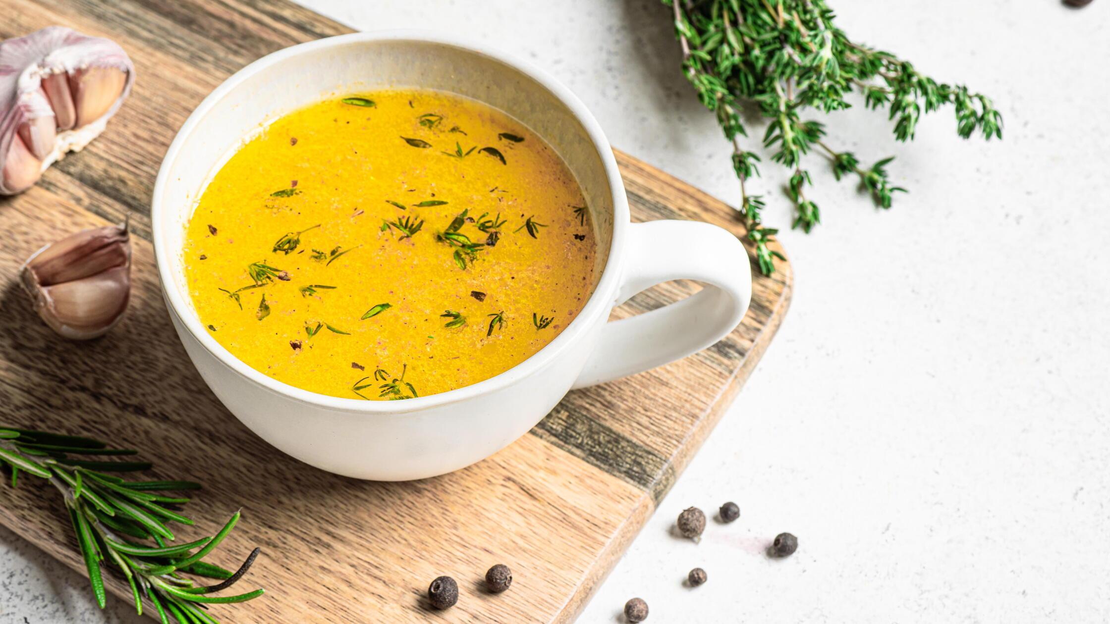Rinderknochenbrühe mit Kräutern im Becher