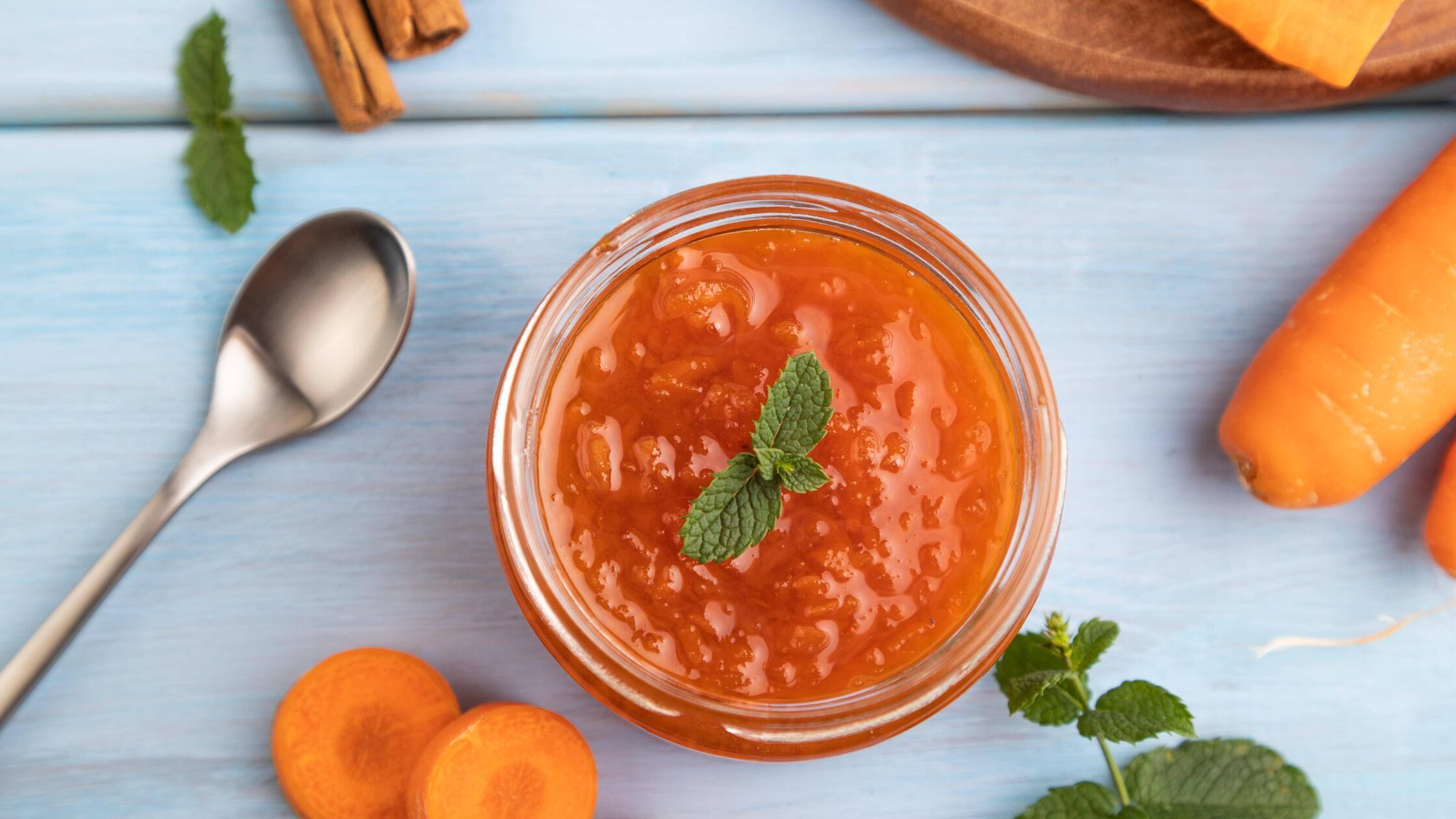 Karottenmarmelade mit Zimt im Glas auf blauem Holz