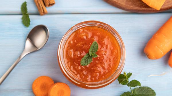 Karottenmarmelade mit Zimt im Glas auf blauem Holz