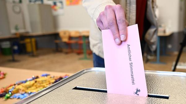 Ein Wähler steckt seinen ausgefüllten Stimmzettel