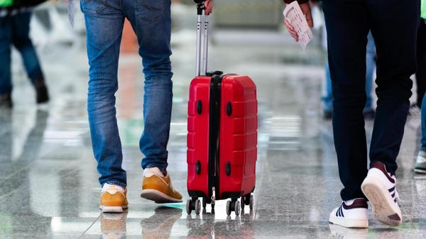 Reisende bewegen sich mit Rollkoffern und Tickets