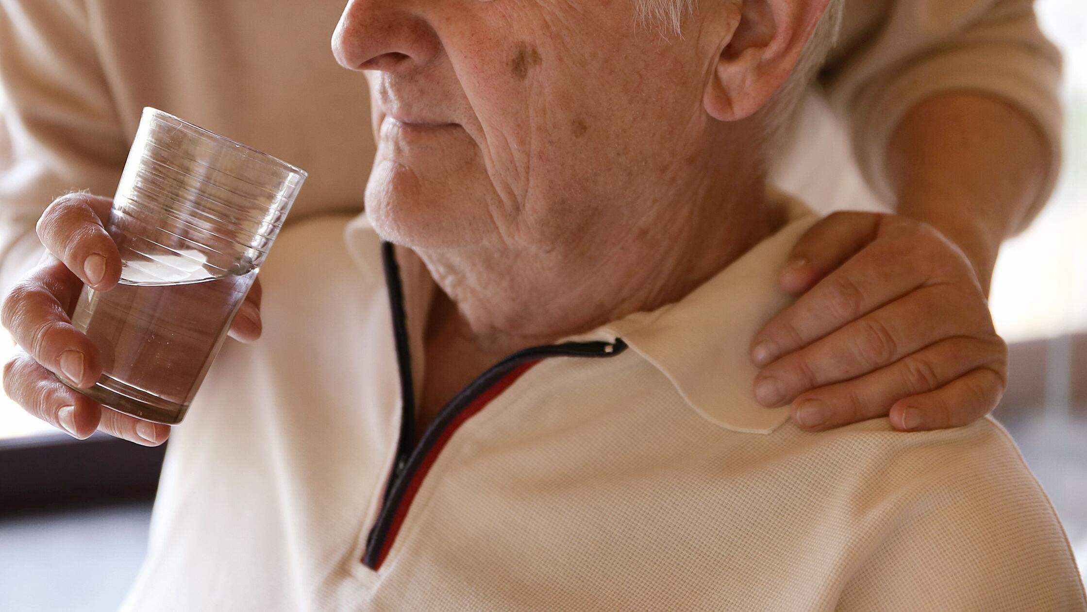 Eine Frau hilft einem Mann beim Trinken659.jpg