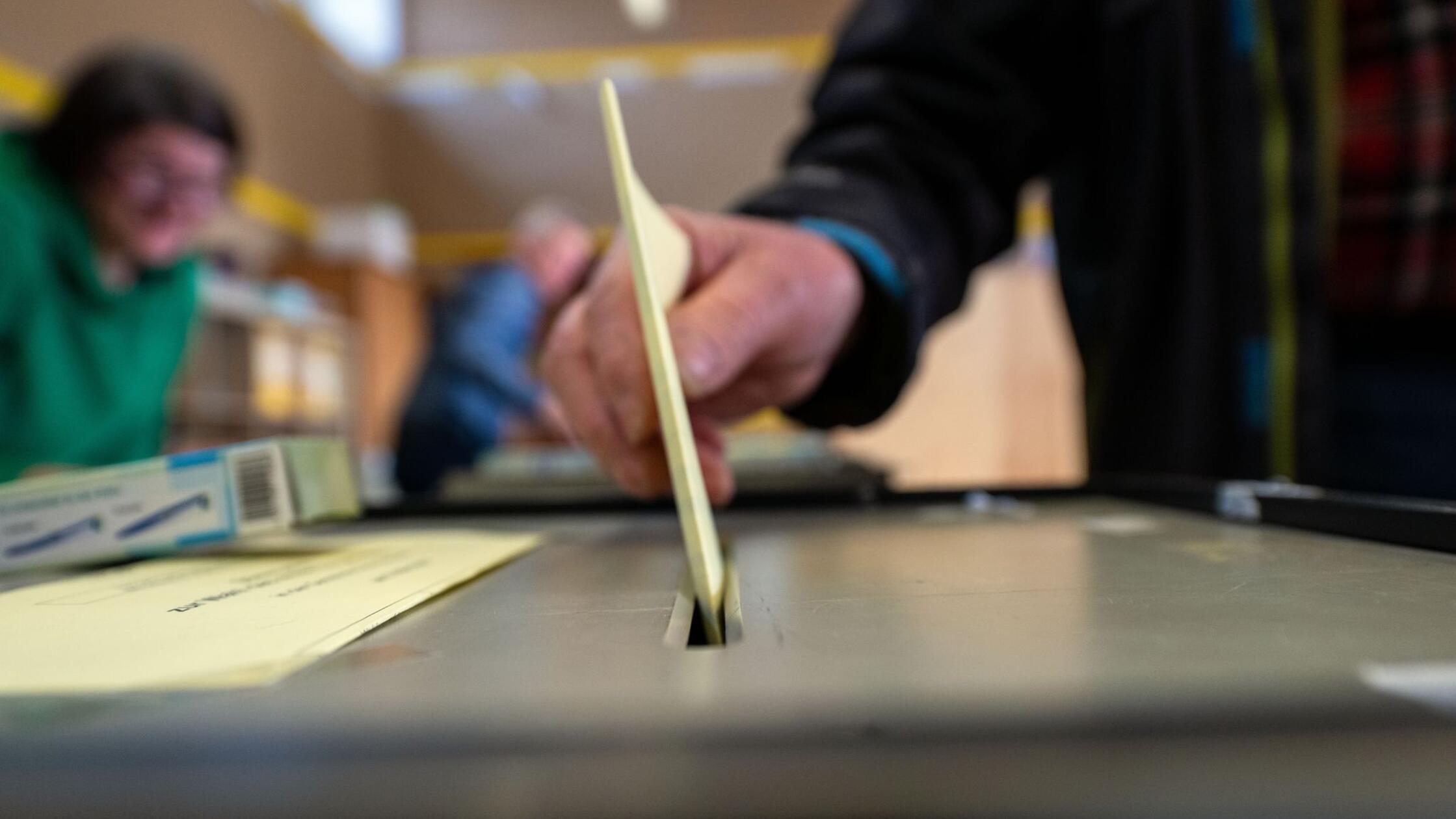 Ein Mann wirft einen ausgefüllten Wahlzettel in ei