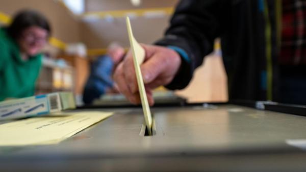 Ein Mann wirft einen ausgefüllten Wahlzettel in ei