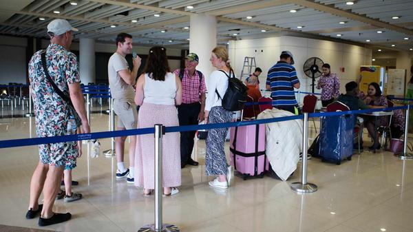 Gestrandete Reisende stehen an einem Informationss