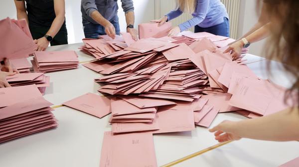Wahlbriefe werden von Wahlhelfern und Wahlhelferin