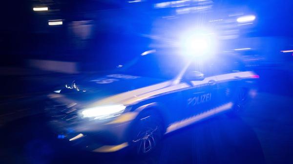 Ein Polizeifahrzeug fährt mit Blaulicht an einem G