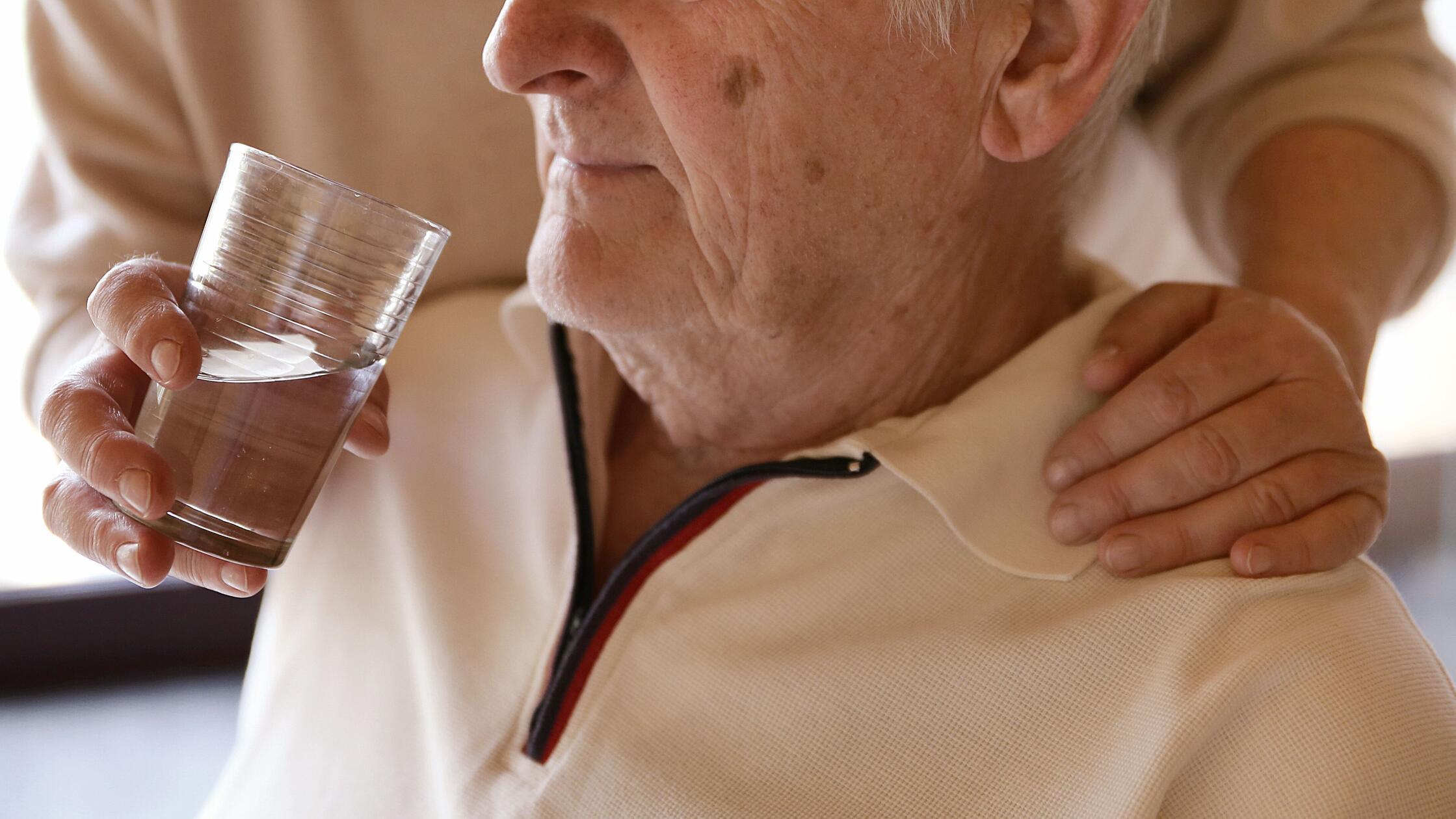 Eine Frau hilft einem Mann beim Trinken