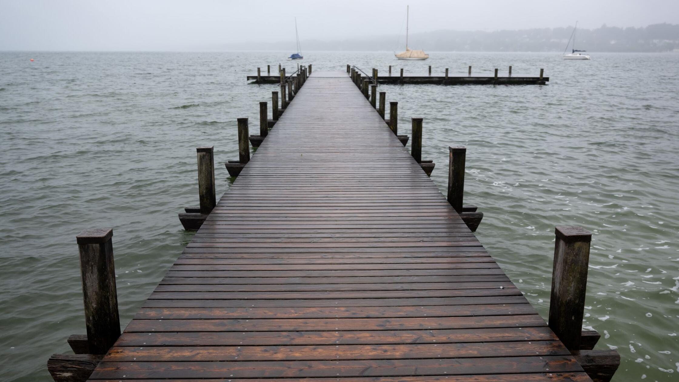 SYMBOLBILD - Dunkle Wolken ziehen über einen Steg 